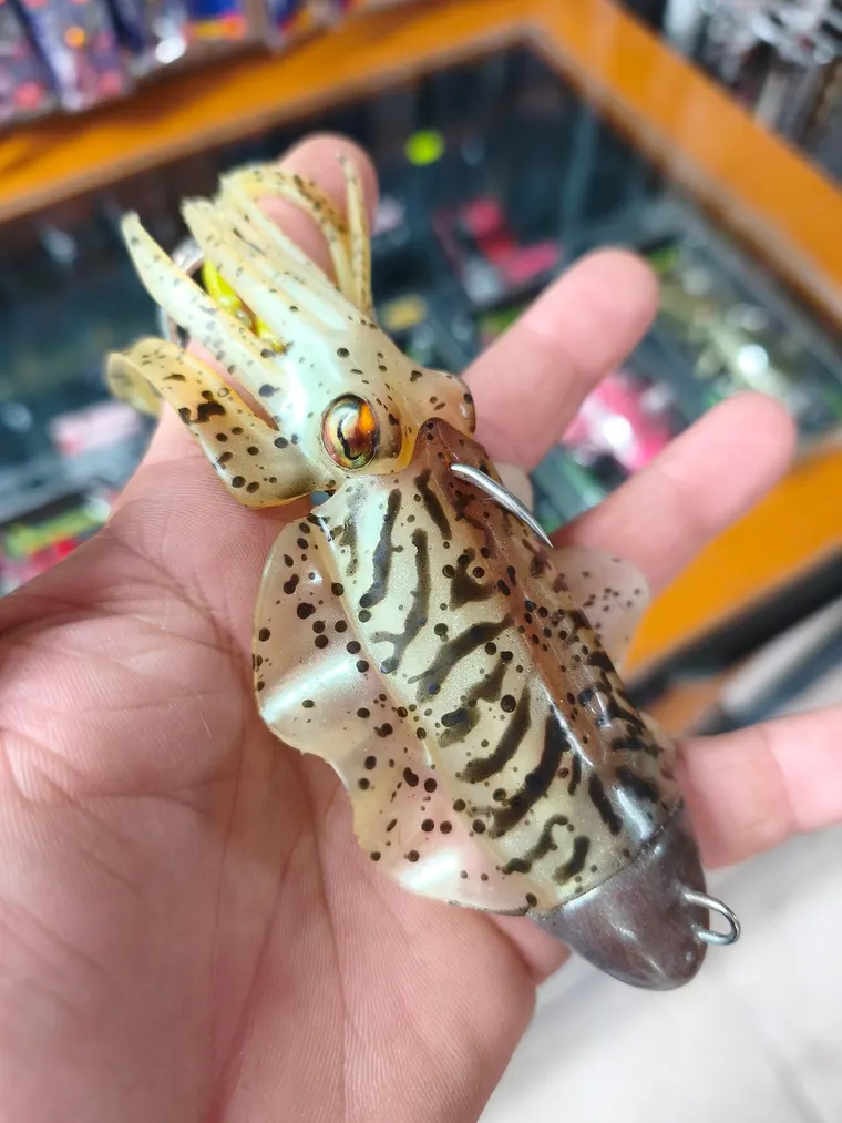 A realistic squid lure held in a hand inside the shop