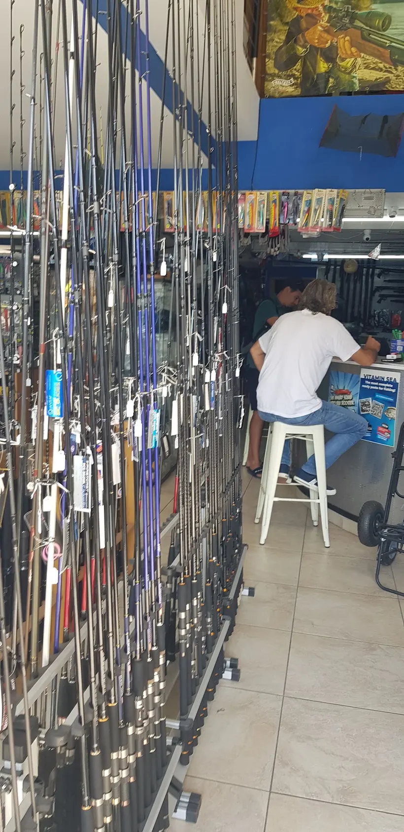 A customer at the Fish Hunter counter, rods racked all around