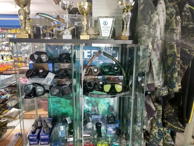Glass case of diving masks with camouflage wetsuits beside it